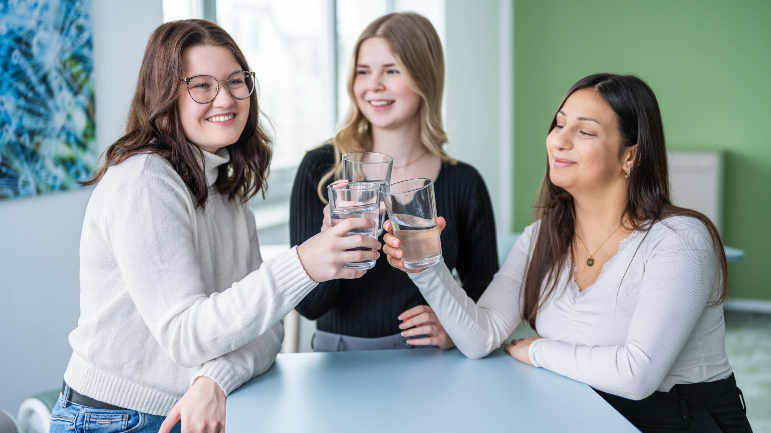 Eine Dreiergruppe stößt mit Trinkwasser an.