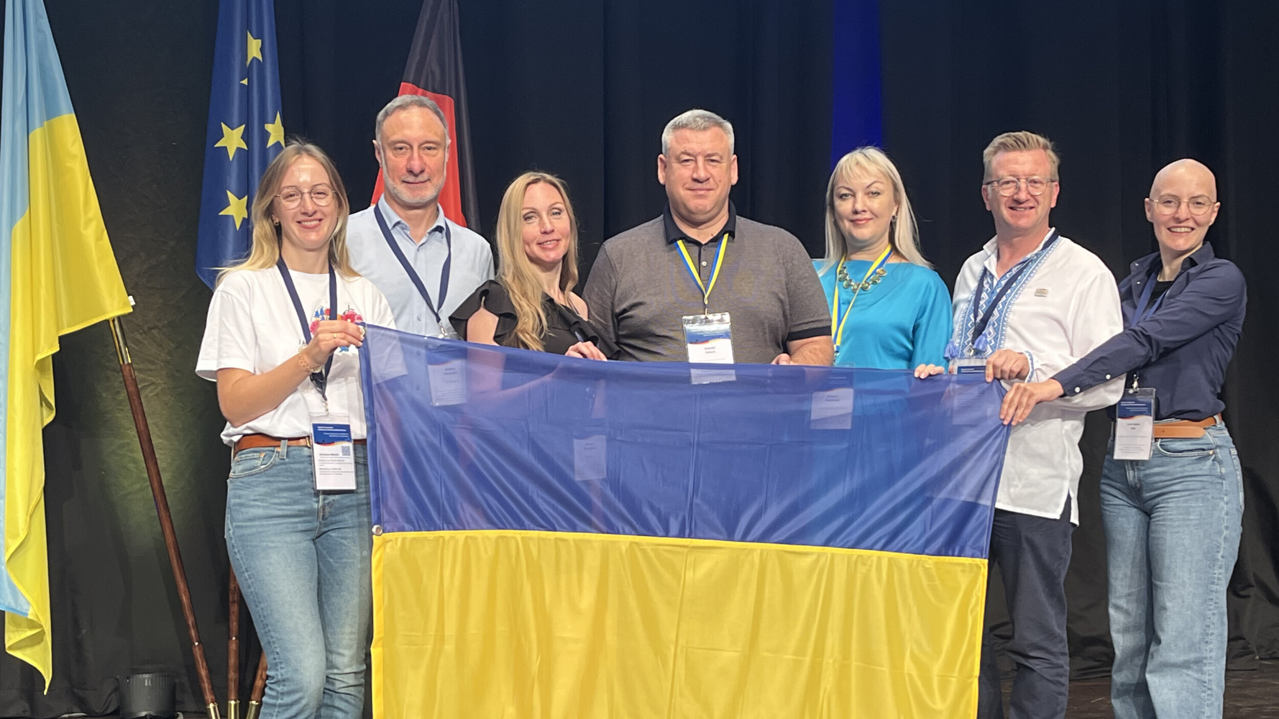 Eine Delegation aus der Ukraine hält zusammen mit zwei Projektteilnehmenden des OOWv die ukrainische Flagge.